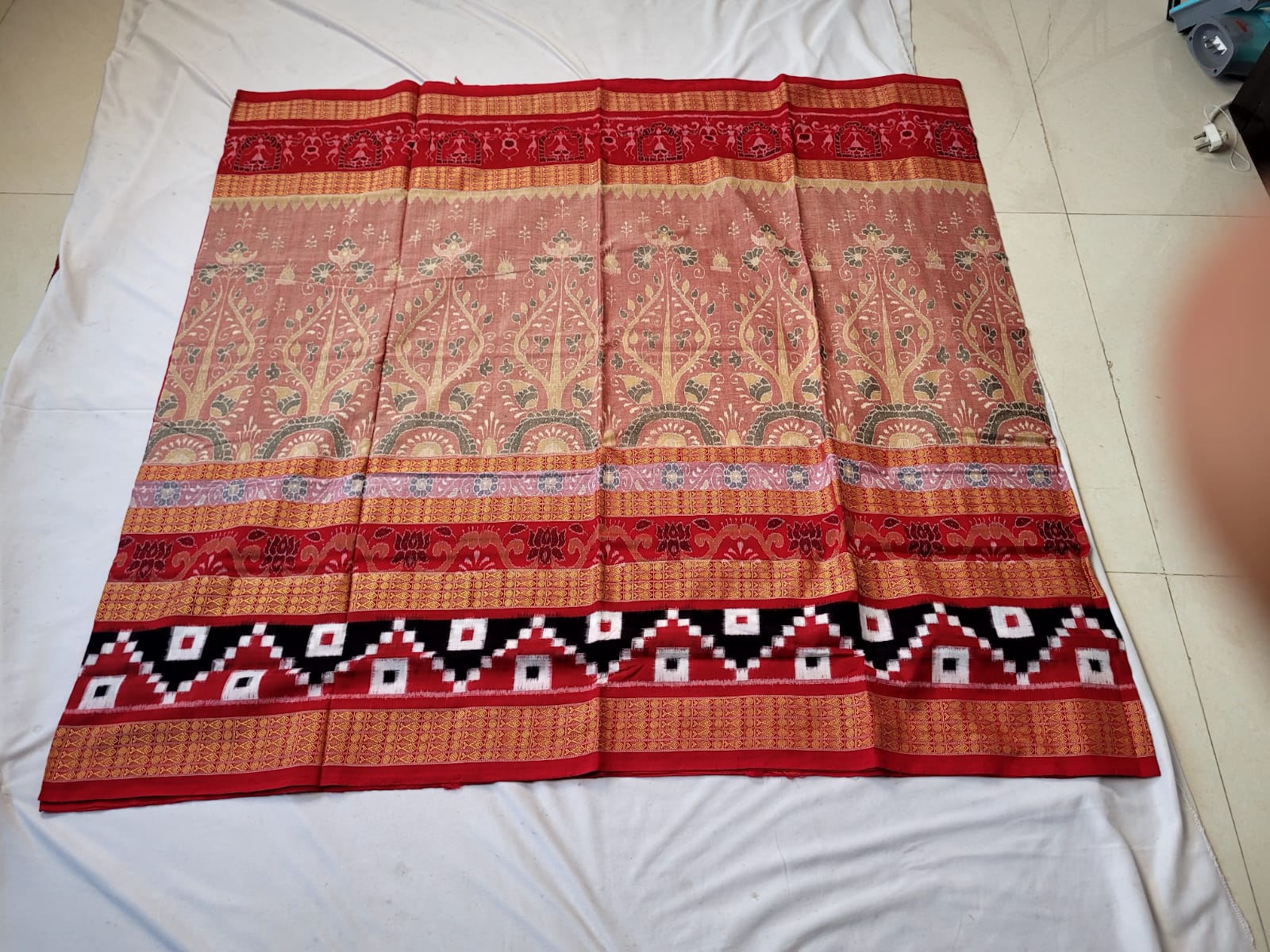 A stunning red and pink Sambalpuri Pasapali saree with a body pattern featuring trees and a pallu adorned with elegant flower designs.