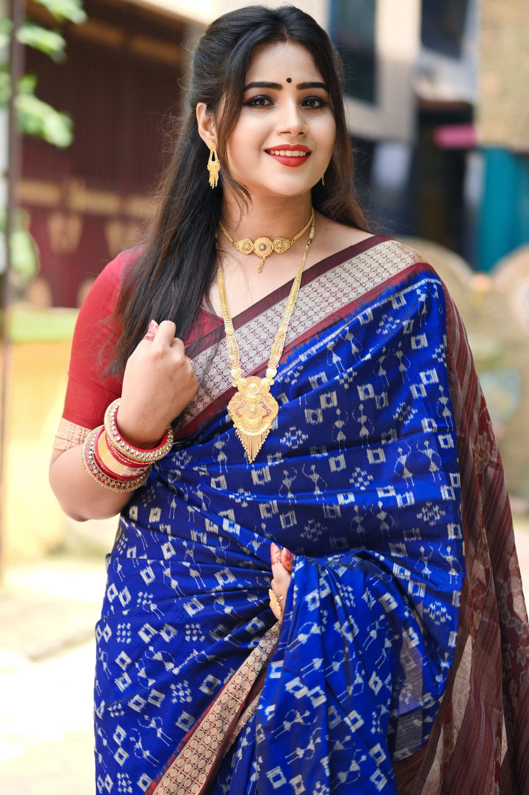 Blue and maroon terracotta with pasapali pattern bandha pata saree, complete with matching blouse piece, radiates traditional charm.