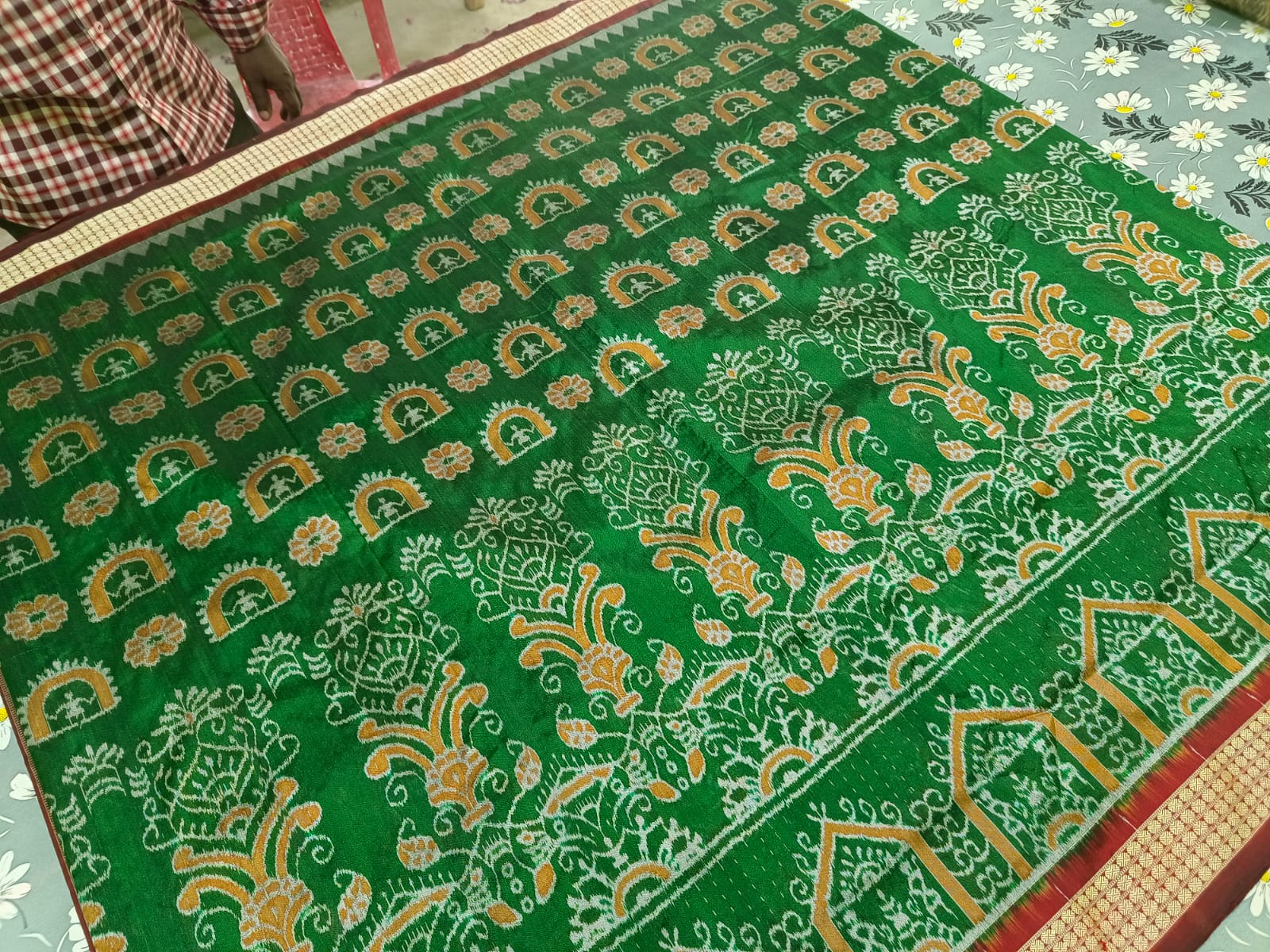 A green and maroon Sambalpuri pata saree featuring a terracotta body pattern with floral designs and a bandha pallu design. Comes with a matching blouse piece.